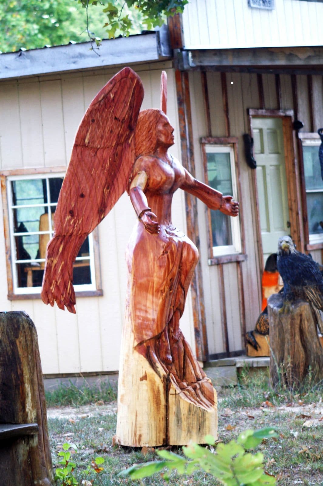 Red cedar angel carving standing outside the workshop