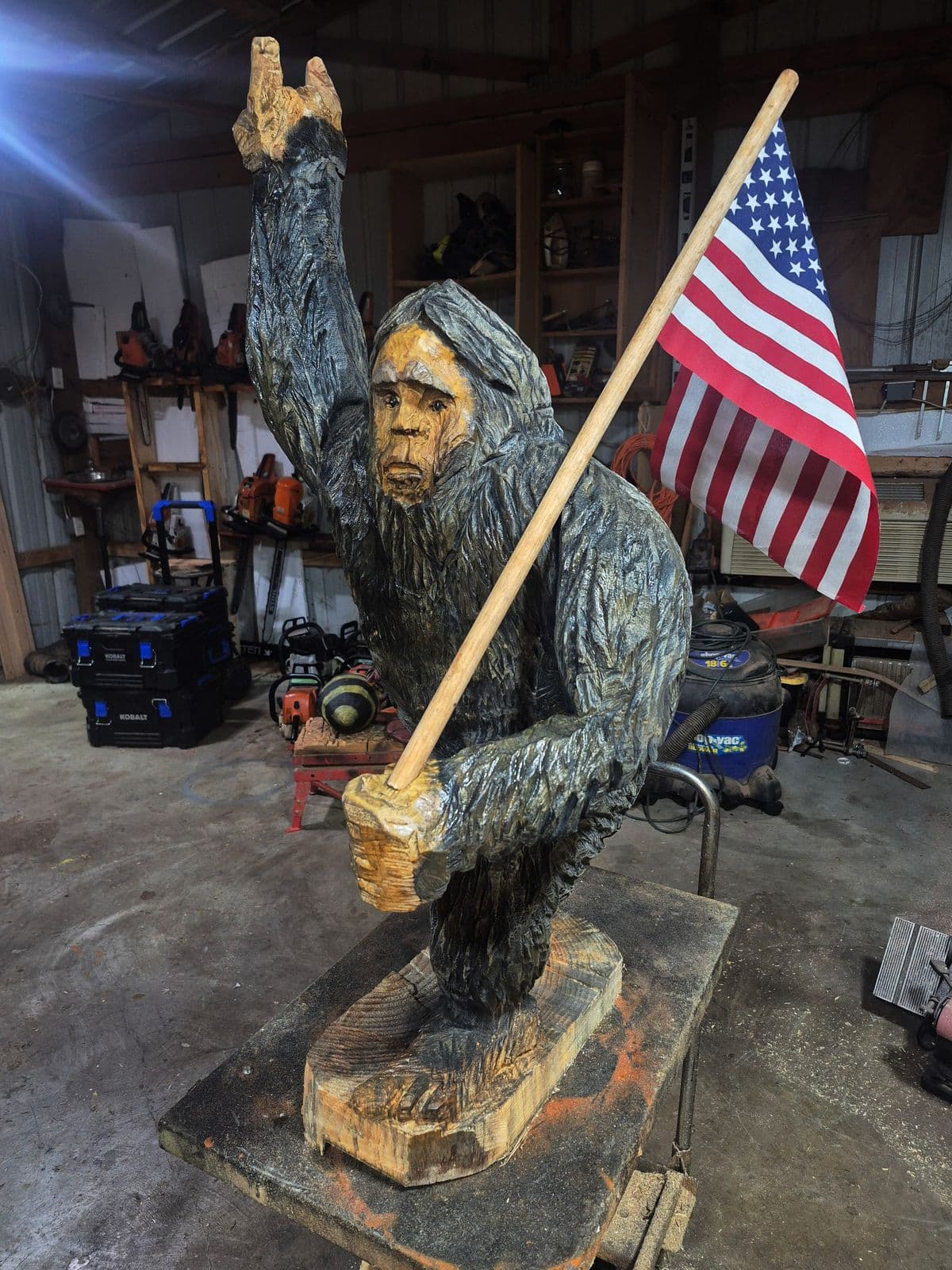 Bigfoot carving waving one arm and carrying an American flag